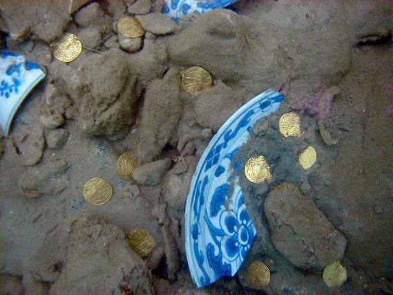 Pièces de monnaies en or et fragments de porcelaine chinoise en cours de dégagement de l’épave du supposé Fiery Dragon 1721, île Sainte-Marie, Madagascar 

