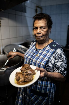 Portrait d'Eva Annibal, créatrice de la recette du canard à la vanille, préparant une assiette dans la cuisine de sa ferme-auberge. 