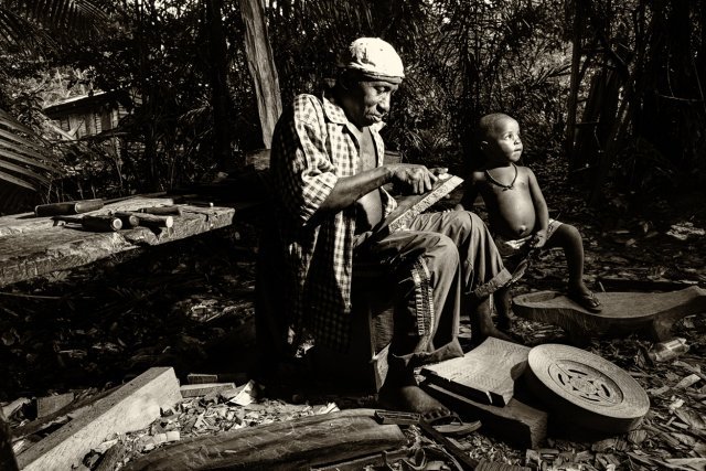 Amiemba Campu, PK 244 RN 1, St Laurent  Aderisson est le responsable d'un village qui compte plusieurs sculpteurs de talent. Il ajuste là  les parties d'un lontu bangi, le banc rond réservé aux femmes, ici orné dans la grande tradition saramaka.
